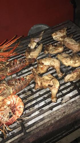 Une bande de poulets et de crevettes cuisinant sur un grill dans l'établissement Kigwedeni Villas, à Nungwi