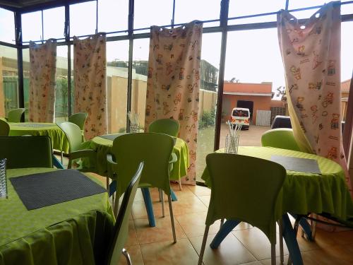 a room with green tables and chairs and windows at Tik Hotel Hoima in Hoima
