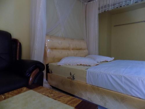 a bedroom with a bed and a chair at Tik Hotel Hoima in Hoima