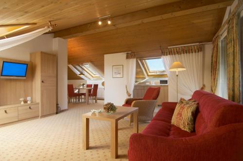 a living room with a red couch and a table at Landhaushotel Hof Wasserkuppe in Poppenhausen