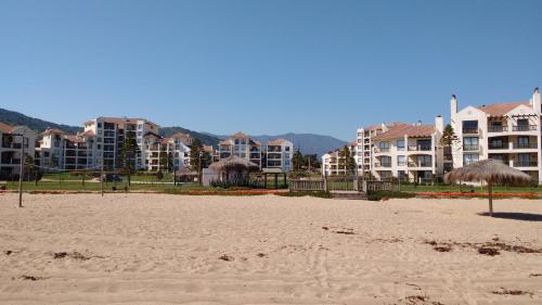 a beach with some umbrellas and some buildings at A Pasos de la Playa in Papudo