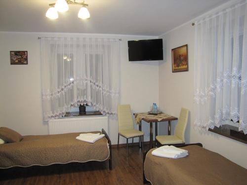 Cette chambre comprend deux lits et une table avec des chaises. dans l'établissement Heveliusz, à Sokołów Podlaski