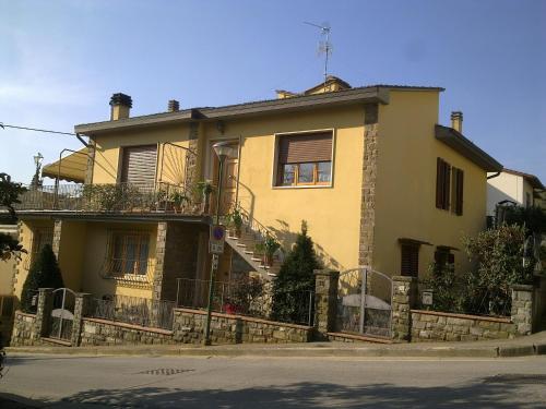 ein großes gelbes Haus mit einem Zaun davor in der Unterkunft Chiantirooms Guesthouse in Greve in Chianti