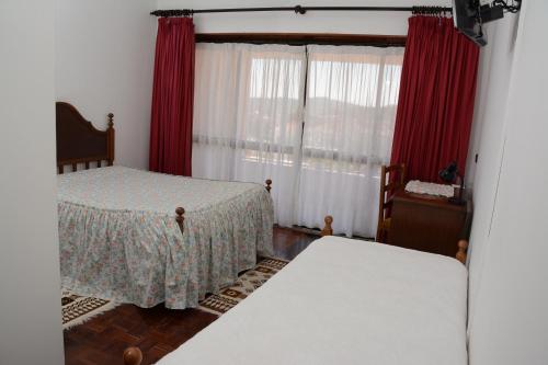 a bedroom with two beds and red curtains at Residencial o Bras in Alvaiázere