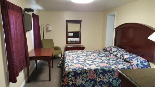 ミドルタウンにあるPleasant Hill Motelのベッド、デスク、椅子が備わるホテルルームです。