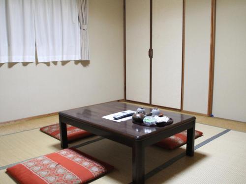 sala de estar con mesa y cojines rojos en Kannawaso, en Beppu