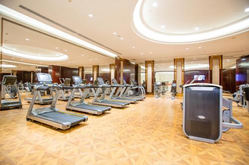 a gym with a row of treadmills and ellipticals at JinLing Hotel SanFangXiang in Jiangyin