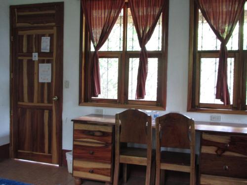 a room with two windows and a desk and two chairs at Finca Ixobel in Ixobel