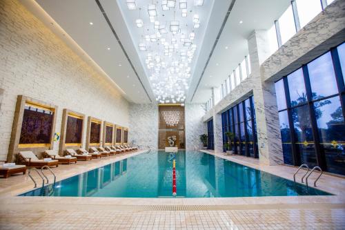 uma grande piscina com cadeiras e um edifício em JinLing Hotel SanFangXiang em Jiangyin