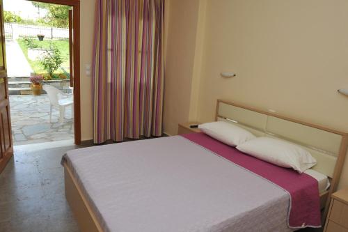 een slaapkamer met een bed en een glazen schuifdeur bij Anna Apartments in Kontokali