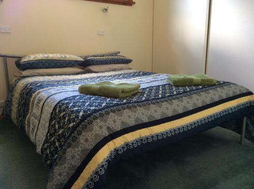 Una cama con dos toallas verdes encima. en Our Cottage, en Ross