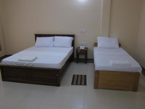 two beds in a small room with sidx sidx sidx sidx at Hotel Oviya in Vavuniya