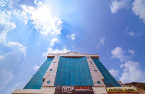 a tall blue building with the sun in the sky at Pepper Residency in Nāgercoil