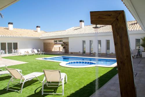 a backyard with a pool and chairs and a house at Casa Boquera in Carche