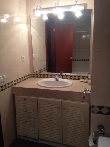 a bathroom with a sink and a large mirror at Apartaments Vicus 1 con vistas a la Plaza Mayor de Vic in Vic