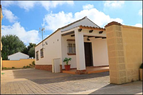 Una casa blanca con una planta en maceta delante de ella. en Bungalow en complejo II, en Conil de la Frontera