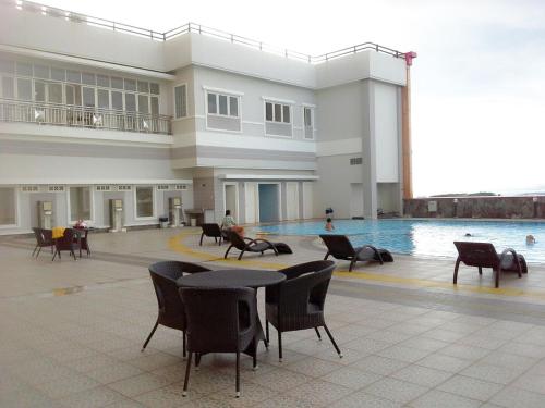 ein großes Gebäude mit einem Pool, Tischen und Stühlen in der Unterkunft Apartemen MTC 623 in Manado