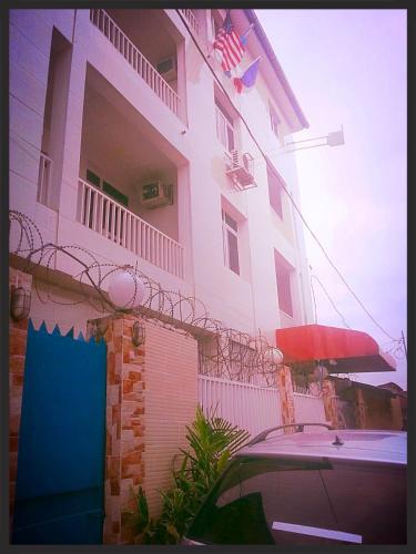 a building with a car parked in front of it at Flat Hôtel Alpha in Kinshasa