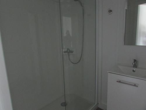 une douche avec une porte vitrée à côté d'un lavabo dans l'établissement Etretat's Motel, à Étretat