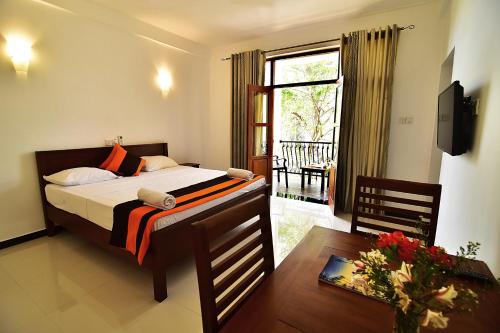 a bedroom with a bed and a table and a window at Park Lane 88 Apartments in Negombo