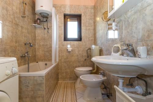 łazienka z umywalką, toaletą i wanną w obiekcie Pool Apartments Julia w mieście Zadar