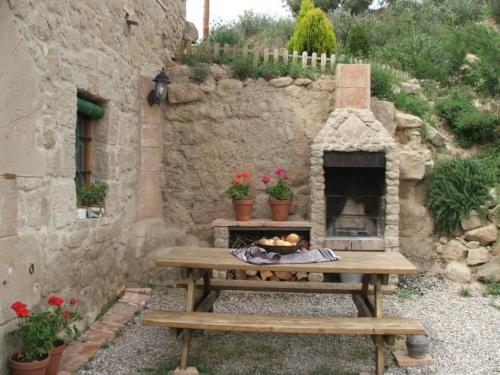 a picnic table in front of a stone building with a fireplace at Cal Viudet Vell in Caserras