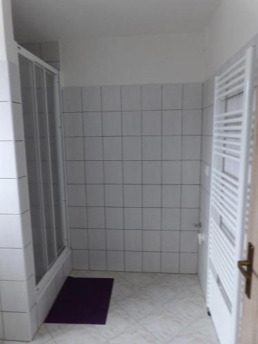 a bathroom with white tiled walls and an open door at Ubytování u Kratochvílů in Dolní Dunajovice