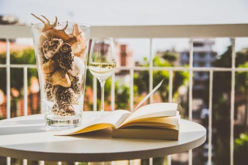 a book and a glass of wine on a table at De La Ville Hotel in Cattolica