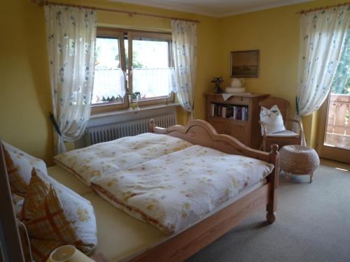 um quarto com uma cama, uma cadeira e janelas em Landhaus Lotte em Halblech