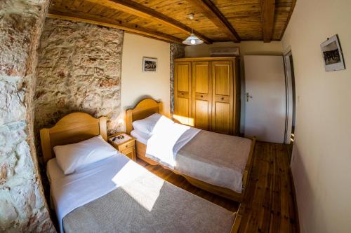 two beds in a room with a stone wall at Ducina Apartments in Milna