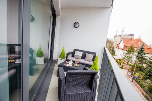 a balcony with two chairs and a table and a couch at Horyzont Luksusowe apartamenty nad morzem z parkingiem Międzyzdroje in Międzyzdroje