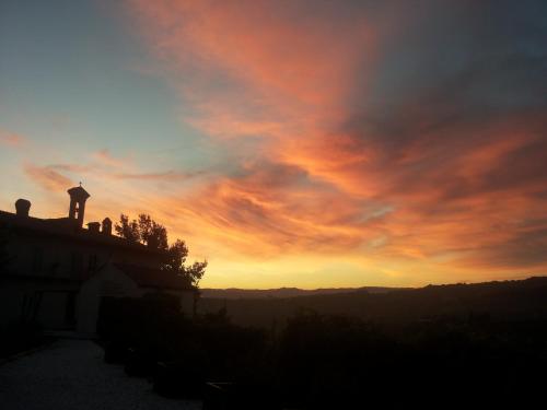 a sunset with a cross on top of a building at Palas Cerequio in La Morra