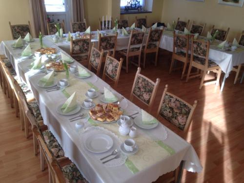 a long dining room with white tables and chairs at Hostel im Osterzgebirge in Kurort Altenberg