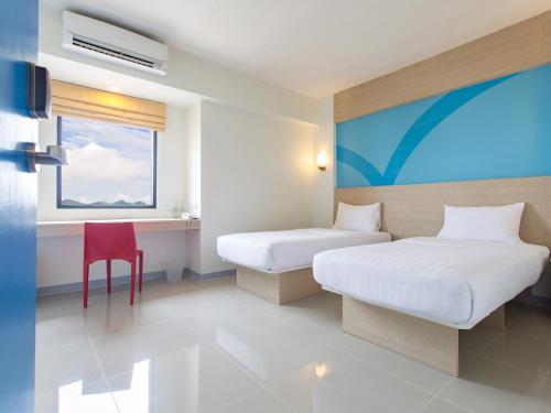 a hotel room with two beds and a red chair at Hop Inn Phuket - SHA Plus in Phuket Town