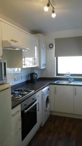 cocina con armarios blancos y fogones en Sunnyside Apartments en Coatbridge