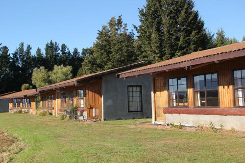 a row of wooden buildings with trees in the background at Barnyard Backpackers Te Anau in Te Anau