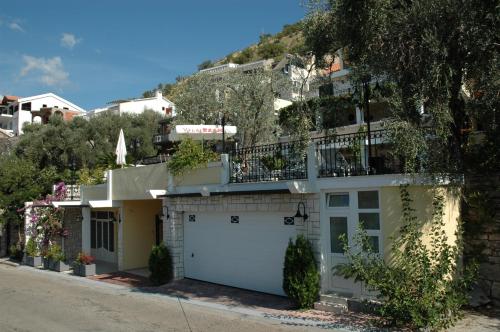 a house with a white garage with a hill in the background at Apartments Balic in Sveti Stefan