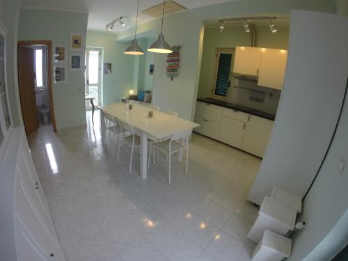 una cucina con tavolo bianco e armadietti bianchi di Casa Vacanze Domus a Centola