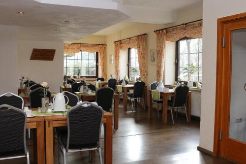a dining room with tables and chairs and windows at Hotel Baldus in Delmenhorst