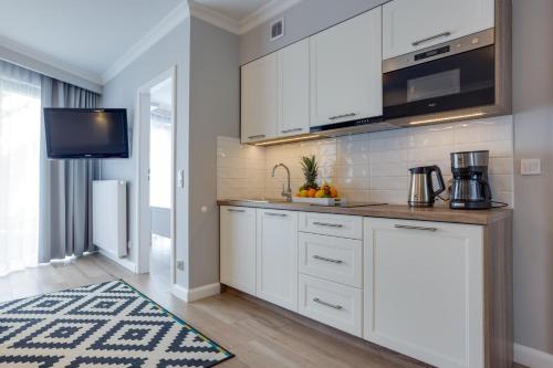 a kitchen with white cabinets and a sink at Horyzont Luksusowe apartamenty nad morzem z parkingiem Międzyzdroje in Międzyzdroje