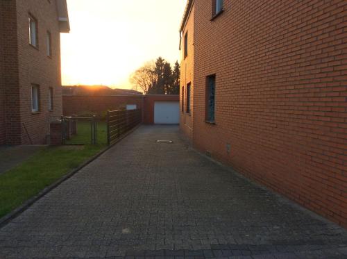 an alley between two brick buildings with the sun setting at Fewo An der Mühlenbachaue in Nettetal