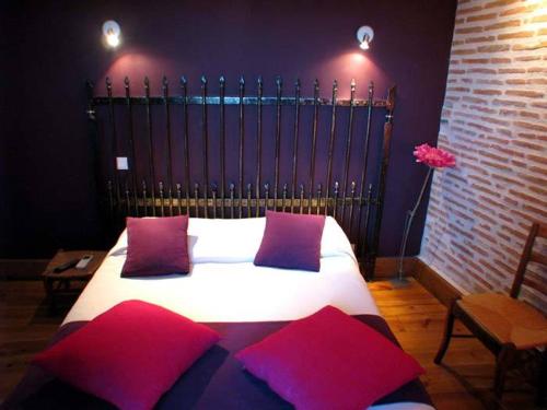 a bedroom with a bed with red and purple pillows at L'Ancien Presbytère in Luzy