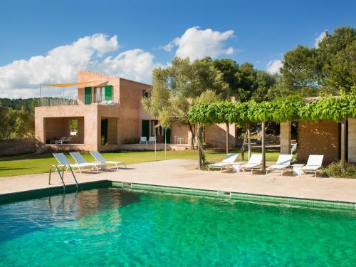 a swimming pool with chairs and a house at Casa Rural Son Bernadinet in Campos