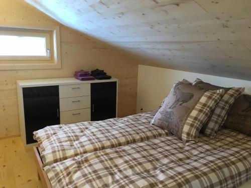 um quarto com uma cama e uma cómoda num sótão em Dem Himmel ein Stuck näher em Thalkirch