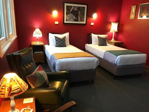 a red room with two beds and a couch at Vine Valley Inn in Cessnock