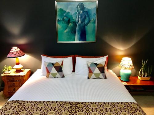 a bedroom with a large white bed with two lamps at Vine Valley Inn in Cessnock