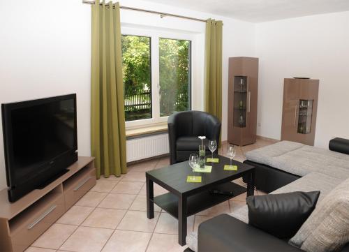 ein Wohnzimmer mit einem Sofa und einem TV in der Unterkunft Appartement Am Goldbichl in Sauerlach