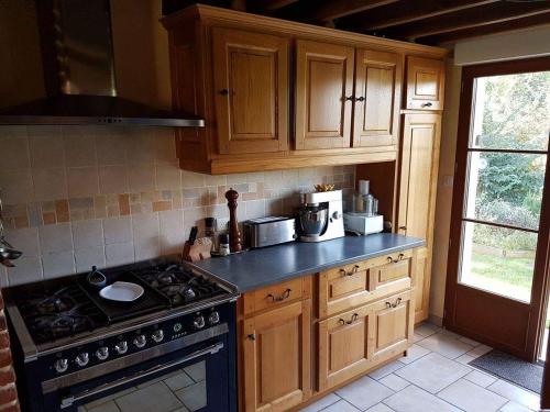 a kitchen with wooden cabinets and a stove top oven at Le Moulin Aux Moines in Croissy-sur-Celle