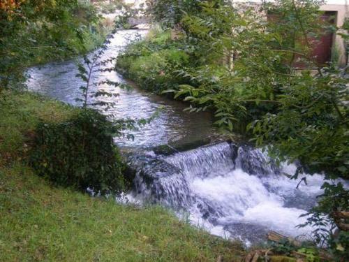 a small stream of water with a waterfall at Le Moulin Aux Moines in Croissy-sur-Celle