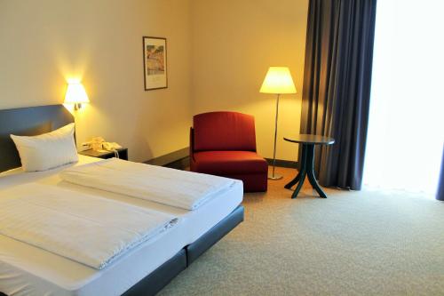 um quarto de hotel com uma cama e uma cadeira vermelha em Hotel Wörth em Wörth an der Isar